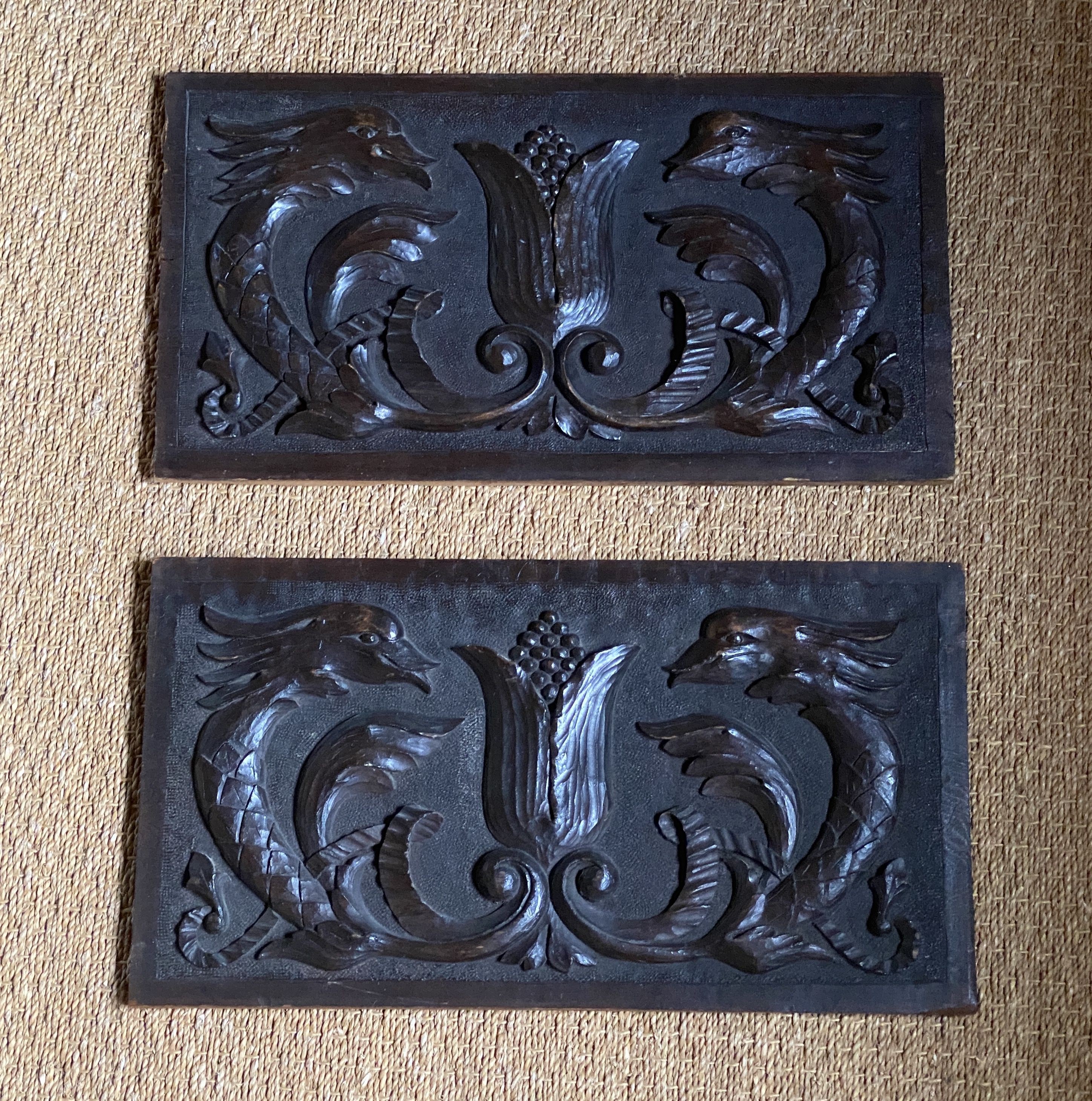 A pair of oak panels carved in relief with stylised dolphins and acanthus, 29 x 53cm